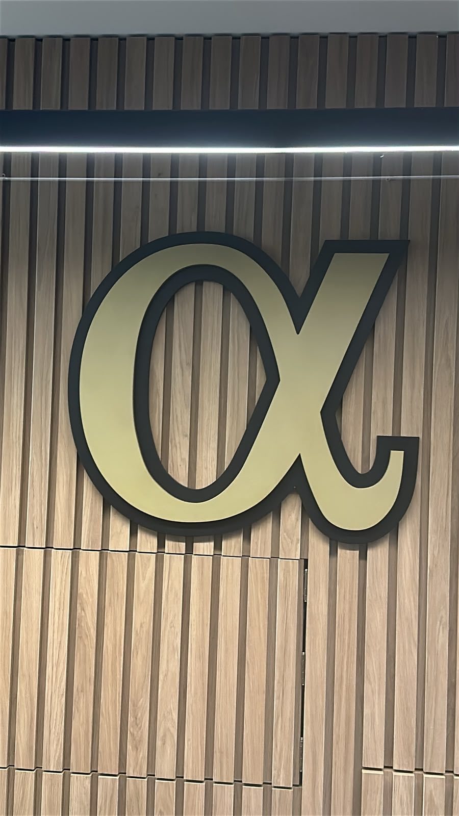 Parede do escritório com a marca alpha da Six Capital Partners