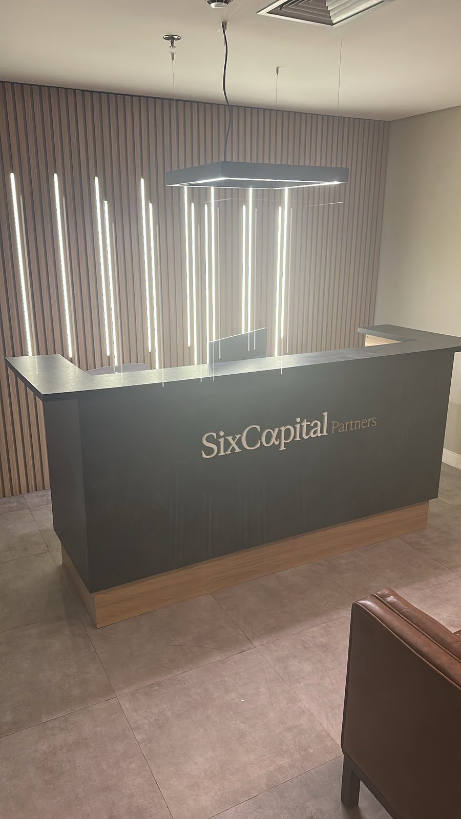 Recepção do escritório da Six Capital Partners com o logotipo no balcão